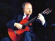 Kai Heumann in suit with cutaway classical guitar, beard and tie
